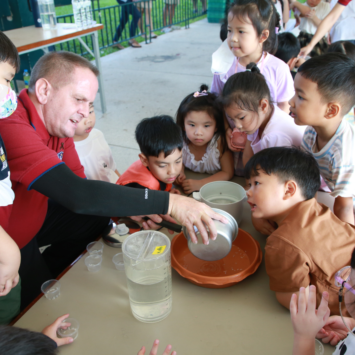 Native English teacher in hands-on experiment with Kindergarten students at Ek Burapa School — play-based learning EP school Bangkok